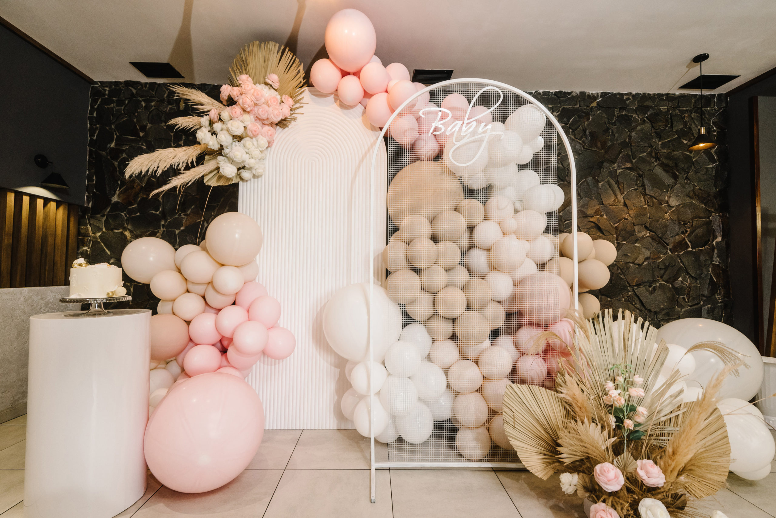 Appetizing desserts near wedding cake decorated with flowers and balloons on pink wall